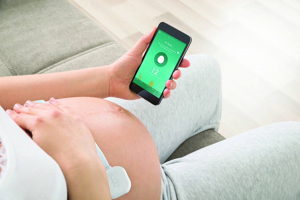 怀孕妇女坐在沙发上用手机与医生视频会议的特写