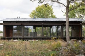 这个涂有柏油的深色木材小屋位于瑞典，以暴露的结构网格为特色